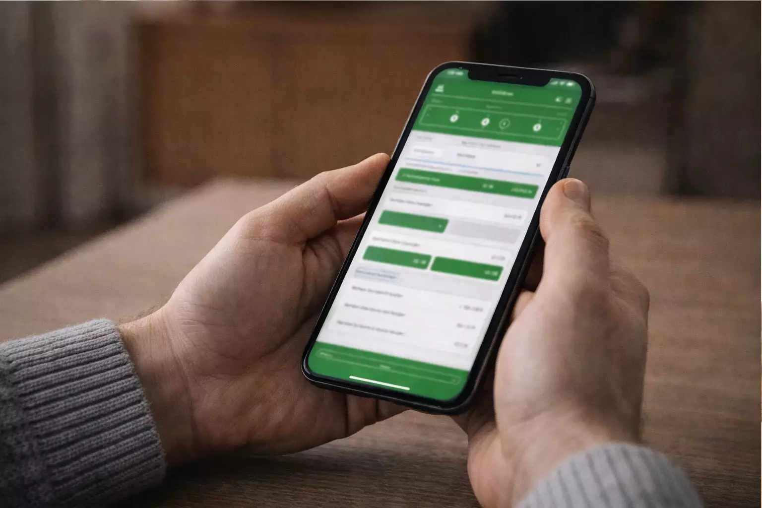 Smartphone mit Sportwetten-App in der Hand eines Nutzers
