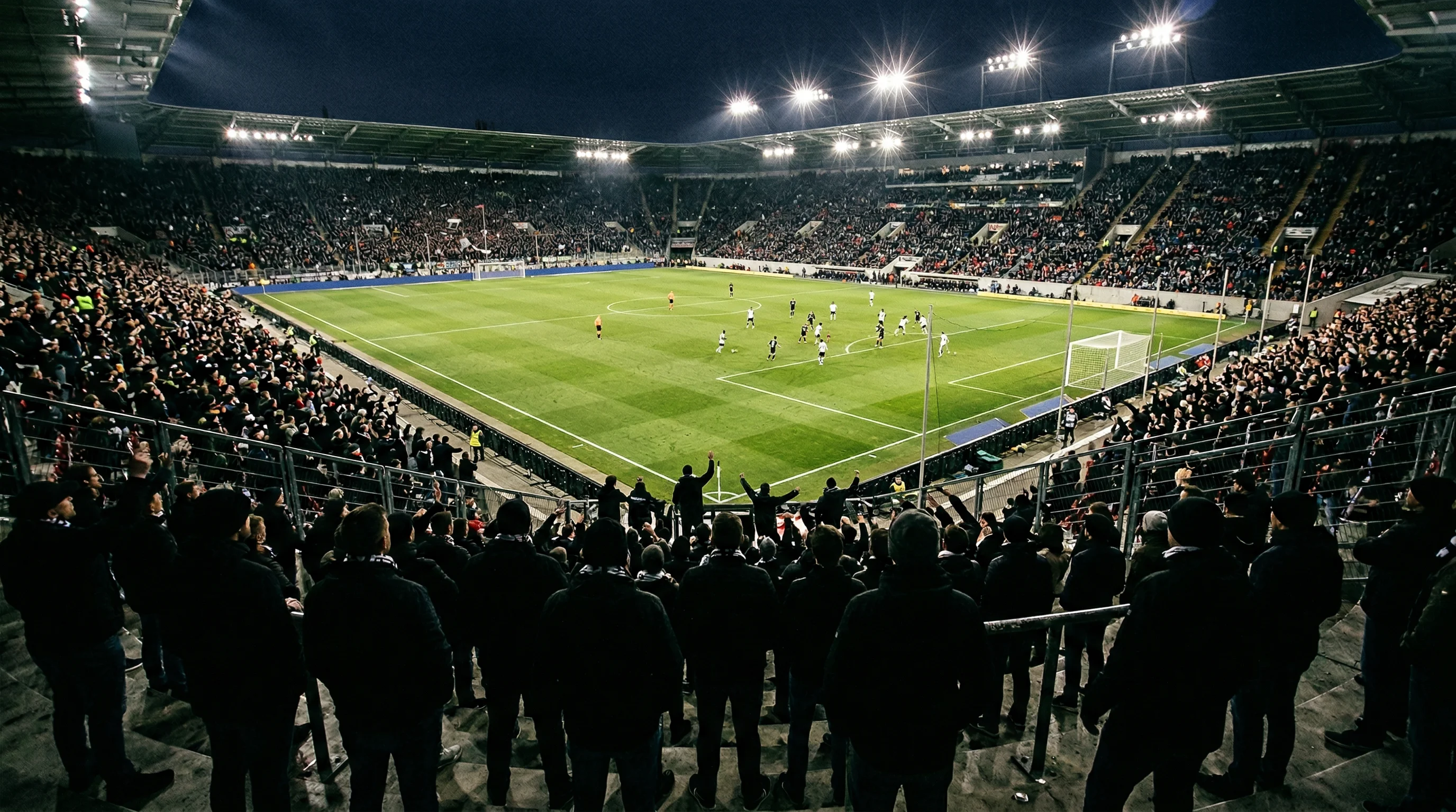 Blick aus der Fankurve auf ein beleuchtetes Fußballfeld während eines Bundesliga-Spiels